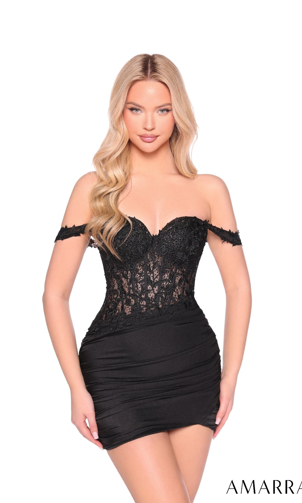 A woman wears the Amarra 88957 Lace-Corset Short Homecoming Dress—an off-the-shoulder black lace mini dress with a sheer corset and ruched skirt—posed against a plain white background.